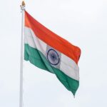Indian national flag waving against a clear sky symbolizing patriotism and pride.