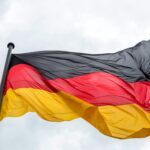 Waving German flag against a cloudy sky, featuring vibrant colors.